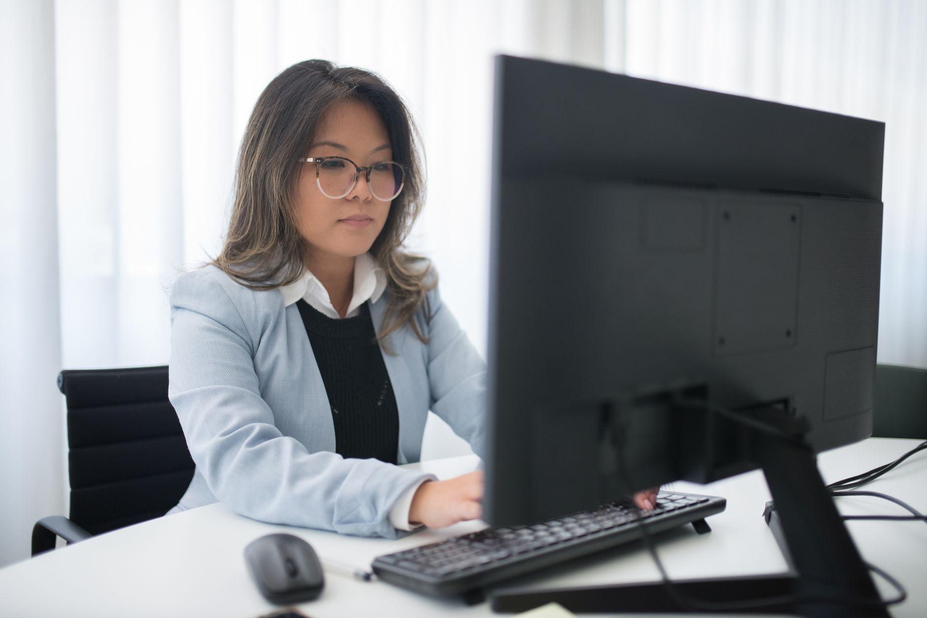 Profissional trabalha diante de um computador em um escritório moderno.