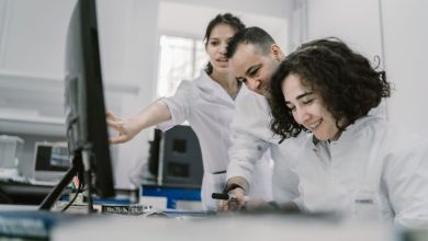 Equipe de pesquisadores trabalha em conjunto diante de um computador em um laboratório moderno.