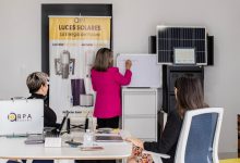 Equipe discutindo soluções de energia solar diante de painéis e quadro branco em um escritório.