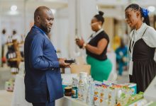 Profissionais conversam em um estande durante uma feira de negócios, com produtos expostos ao público.