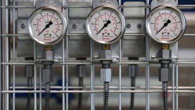 Medidores de pressão industriais instalados em uma grade metálica no interior de uma fábrica