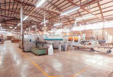 Vista ampla do interior de uma fábrica brasileira organizada, com máquinas e estruturas industriais.