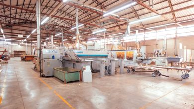 Vista ampla do interior de uma fábrica brasileira organizada, com máquinas e estruturas industriais.